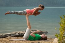 Coppia sportiva che pratica acro yoga vicino alla costa del mare in una giornata di sole — Foto stock
