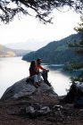 Casal situando juntos na rocha perto do lago — Fotografia de Stock