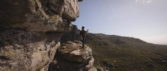 Wanderer, der an einem sonnigen Tag auf einer Klippe steht und Fotos macht — Stockfoto