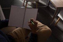 Mid section of male executive writing on diary in the office — Stock Photo