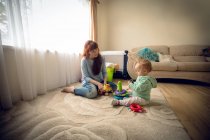 Матір з її дитину Дівчинка, граючи з іграшками в домашніх умовах — стокове фото
