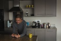Молодой человек использует мобильный телефон дома — стоковое фото