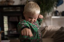 Vorschulkind führt Kampfkunst im heimischen Wohnzimmer vor. — Stockfoto