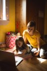Мать и дочь используют ноутбук в спальне дома — стоковое фото