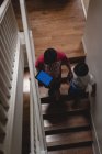 Frères et sœurs marchant avec une tablette numérique dans les escaliers à la maison — Photo de stock