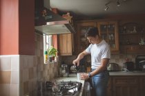 Чоловік наливає каву в кухоль на кухню вдома . — стокове фото