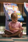 Мила дівчина читає книгу в магазині — стокове фото