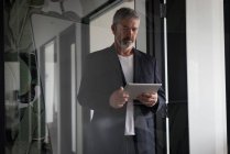Hombre de negocios atento utilizando tableta digital en la oficina creativa - foto de stock