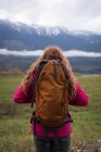 Вид сзади женщины с рюкзаком, смотрящей на заснеженные горы — стоковое фото