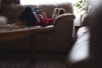 Мальчик использует цифровой планшет с наушниками в гостиной дома — стоковое фото