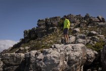 Escursionista in piedi sulla scogliera in una giornata di sole — Foto stock