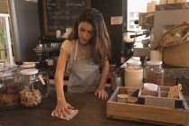 Camarera limpiando la mesa en la cafetería - foto de stock