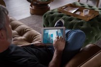 Männlicher Büroleiter mit digitalem Tablet auf Sofa im Kreativbüro — Stockfoto
