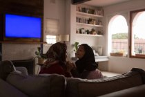Playful Muslim mother and daughter holding hands on sofa at home — Stock Photo
