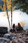 Coppia seduta insieme sulla roccia vicino al lago — Foto stock