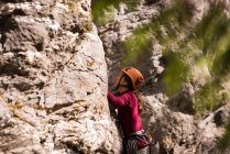 Визначений жіночий альпініст, що піднімається скелястою скелею — стокове фото