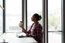 Удумлива жінка-виконавця, що має чашку кави в офісі — стокове фото