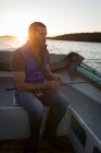 Продуманий чоловік зав'язує рибальський стрижень у моторному човні під під підсвічуванням . — стокове фото