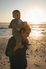 Madre e figlio divertirsi in spiaggia durante il tramonto — Foto stock