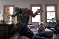 Отец поднимает сына, играя с детьми в гостиной на дому
. — стоковое фото