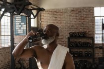 Müder Senior trinkt Wasser im Fitnessstudio. — Stockfoto