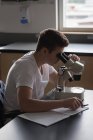 Мальчик-подросток экспериментирует на микроскопе в лаборатории университета — стоковое фото