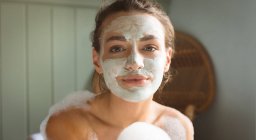 Frau mit Gesichtsmaske badet im heimischen Badezimmer. — Stockfoto