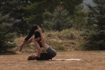 Mujeres deportistas practicando acro yoga en campo abierto en un día soleado - foto de stock