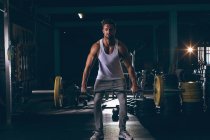 Retrato de homem musculoso exercitando com barbell no estúdio de fitness — Fotografia de Stock