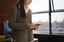 Esecutivo femminile utilizzando sul telefono cellulare in ufficio — Foto stock