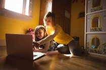 Мать и дочь используют ноутбук в спальне дома — стоковое фото