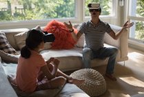 Padre e hija usando auriculares de realidad virtual en la sala de estar en casa - foto de stock