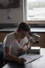 Adolescente experimentando microscópio em laboratório na universidade — Fotografia de Stock