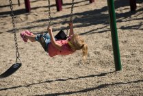 Jolie fille jouer sur swing dans parc — Photo de stock