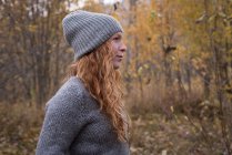 Mulher bonita em roupas quentes em pé na floresta de outono — Fotografia de Stock