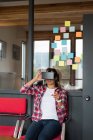 Женщина-руководитель сидит на стуле и использует гарнитуру виртуальной реальности в офисе — стоковое фото