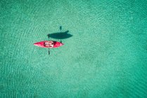 Каякер плавает на байдарках по мелкой бирюзовой воде в солнечный день — стоковое фото