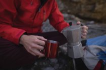 Primer plano de la mano excursionista verter bebida en taza - foto de stock
