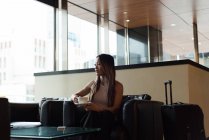 Бізнес-леді сидить на самоті, дивлячись далеко, маючи каву в вестибюлі — стокове фото