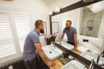 Mann steht vor Spiegel und überprüft sich im Badezimmer — Stockfoto