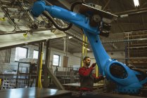 Чоловік працівник перевіряє роботизовану машину на заводі — стокове фото