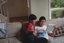 Irmãos usando tablet digital na sala de estar em casa — Fotografia de Stock