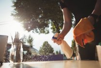 Worker spraying water while cleaning table at outdoor cafe — Stock Photo