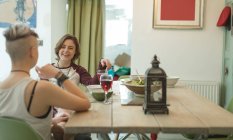 Coppia lesbica che cena con bicchieri di vino rosso nel moderno soggiorno . — Foto stock