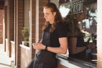 Proprietário usando telefone celular no café exterior — Fotografia de Stock