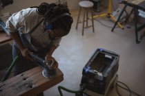 Hochwinkelaufnahme des Tischlers, der Holz mit Poliermaschine in der Werkstatt nivelliert — Stockfoto