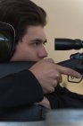 Close-up of man aiming sniper rifle at target in shooting range — Stock Photo