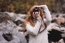 Mulher ruiva fotografando na floresta — Fotografia de Stock