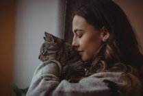 Close-up of beautiful woman smelling her pet cat at home — Stock Photo