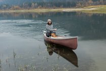 Hombre canoa rugiente en el río con su perro - foto de stock